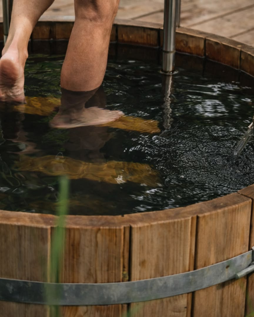 Person stepping into a wooden cold plunge tub